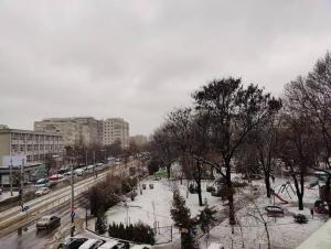 une rue de la ville avec de la neige au sol et des voitures dans l'établissement Apartament The Cozy Nest Turda, à Bucarest