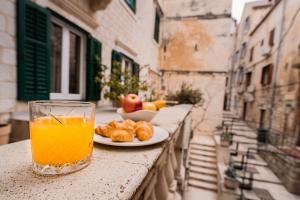 a glass of orange juice sitting on a table with a plate of food at Slavija Culture Heritage Hotel in Split