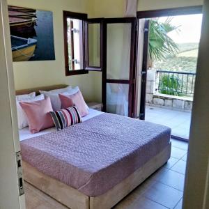 ein Schlafzimmer mit einem Bett mit rosa Kissen und einem Balkon in der Unterkunft Country Bellavista Darmarohori in Darmarochori