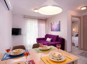 een woonkamer met een tafel en een paarse bank bij Lena Apartments 3 in Potos