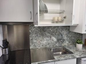 una cocina con fregadero de acero inoxidable y armarios blancos en Apartamento a 100 m de la playa! en Torroella de Montgrí