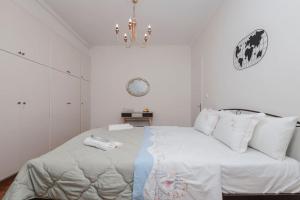 een witte slaapkamer met een groot bed en een kroonluchter bij M&R HOME in Mantoúkion