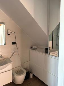 a white bathroom with a toilet and a sink at Kingfish restaurant & boutique hotel in Patog