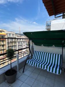 a bench on a balcony with a green canopy at Gnaios penthouse in Thessaloniki