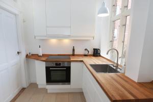 a kitchen with white cabinets and a sink at Scandi-Hygge Seaside House - only 10mins to Copenhagen in Charlottenlund