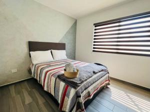 1 dormitorio con 1 cama con manta y ventana en Hermoso y nuevo departamento, en Cuautitlán Izcalli