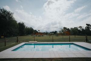 a swimming pool in the middle of a field at Casa Brunia Lago Los Molinos in Villa General Belgrano