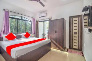 a bedroom with a bed with red pillows and a window at Calangute Ocean Wave in Baga