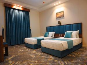 duas camas num quarto de hotel com cortinas azuis em انباك للشقق المخدومه em Abha