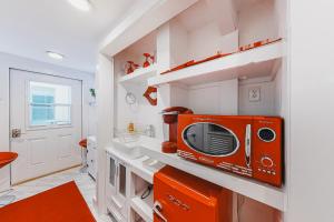 uma pequena cozinha com um micro-ondas laranja numa prateleira em Captivating Cottage em Provincetown
