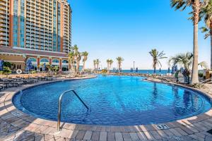 a large swimming pool with palm trees and the ocean at Portofino #2009 in Pensacola Beach