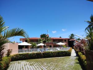 a resort with tables and umbrellas in front of it at Pousada Flats Recanto Sonhos do Porto in Porto De Galinhas