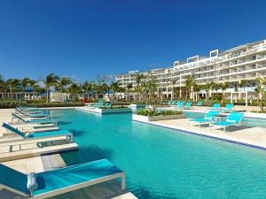 un complejo con piscina con sillas azules y un edificio en Margaritaville Island Reserve Cap Cana Wave - An All-Inclusive Experience for All, en Punta Cana