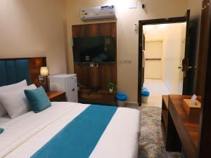 a bedroom with a large bed and a television at انباك للشقق المخدومه in Abha