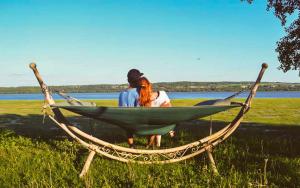 2 personnes assises dans un hamac dans un champ dans l'établissement Lofts Fleuve et Montagnes, à Sainte-Anne-de-Beaupré