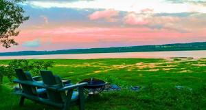 een paar stoelen in het gras bij een meer bij Lofts Fleuve et Montagnes in Sainte-Anne-de-Beaupré