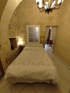 a bedroom with a large bed and a chandelier at Charming rustic getaway in Xaghra, Gozo. in Xagħra