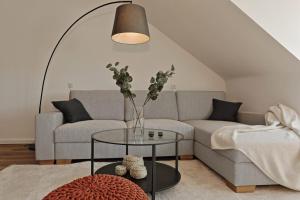 a living room with a couch and a table with a vase at Stylish 3BR apartment -10min to Hbf, full kitchen, homeoffice, Netflix, Wifi in Düsseldorf