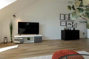 a living room with a flat screen tv on a white cabinet at 'Traveller lodge' großzügiges Apartment - 3 BR, 10min to Hbf, full kitchen, homeoffice, Netflix, Wifi in Düsseldorf