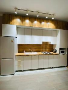 eine Küche mit weißen Schränken und einem Kühlschrank in der Unterkunft Уютные апартаменты центр города в новом ЖК Арман in Atyrau