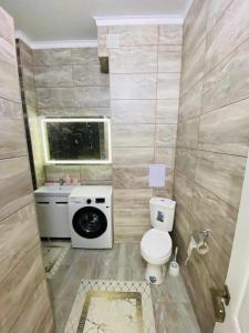 ein Bad mit einem WC, einem Waschbecken und einem Fenster in der Unterkunft Уютные апартаменты центр города в новом ЖК Арман in Atyrau