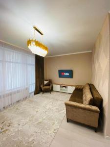 ein Wohnzimmer mit einem Sofa und einem TV in der Unterkunft Уютные апартаменты центр города в новом ЖК Арман in Atyrau