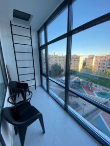 Zimmer mit einem Stuhl und einem großen Fenster in der Unterkunft Уютные апартаменты центр города в новом ЖК Арман in Atyrau