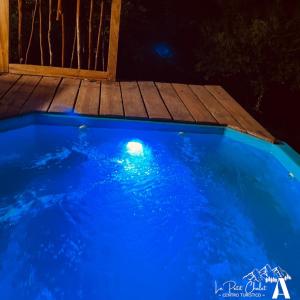 a blue swimming pool at night with a wooden deck at Cabaña Sector La placeta, VII R. in El Torreón