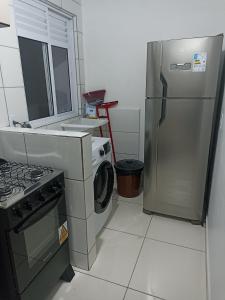 cocina con nevera y lavadora en Condomínio Residencial Mar Azul, en Imbituba