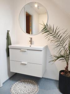 La salle de bains est pourvue d'un lavabo blanc et d'un miroir. dans l'établissement Dronninglund Appartements, à Dronninglund