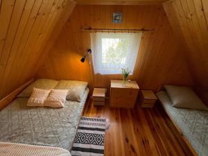 two beds in a wooden room with a window at Domek Danusia z dwiema sypialniami in Władysławowo