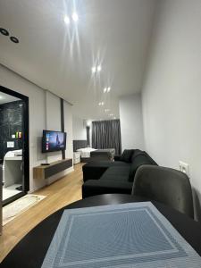 ein Wohnzimmer mit einem Sofa und einem TV in der Unterkunft CozyStayApartments in Tirana