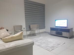 a living room with a couch and a flat screen tv at SBJ Place East Legon in Accra