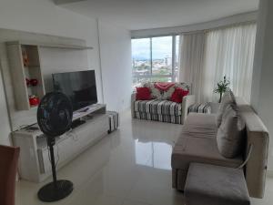 a white living room with a couch and a tv at Confortável apartamento na praia in Capão da Canoa