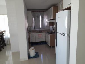 uma cozinha com um frigorífico branco num quarto em Confortável apartamento na praia em Capão da Canoa