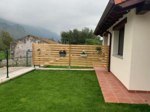 un patio trasero con una valla de madera y césped verde en Apartamentos Cañamal en Llanes