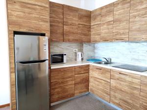 een keuken met een roestvrijstalen koelkast en houten kasten bij Skyline View Apt & Pool Retreat in Budva