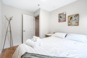 a white bedroom with a bed with towels on it at Luxury Delta 2BD Suit on ground floor in Delta