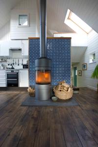 a fireplace in the middle of a kitchen with wooden floors at Driftwood Cottage, Findhorn Village in Forres