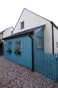 a blue building with two windows and a fence at Driftwood Cottage, Findhorn Village in Forres