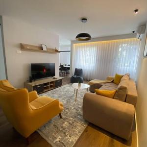 uma sala de estar com um sofá e cadeiras e uma televisão em Rita Apartment in the heart of Pristina,Kosovo em Pristina