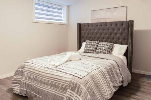 a bedroom with a bed with a blanket and a window at Condo in Southeast Calgary in Calgary