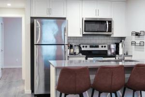 a kitchen with a refrigerator and a counter with chairs at Condo in Southeast Calgary in Calgary