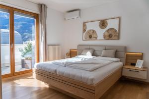 a bedroom with a bed and a large window at Luxus Penthouse mit Terrasse, Garage, Fahrradraum und Infrarotsauna in Merano