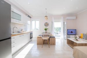 a kitchen with white cabinets and a table with a chair at Corfu City Apartments in Corfu Town