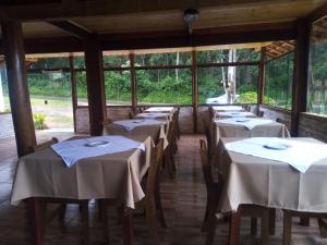 a row of tables in a room with windows at Pousada Duplátanos in Monte Verde