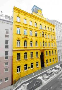 żółty budynek z samochodami zaparkowanymi przed nim w obiekcie Apartment Trappelgasse w Wiedniu