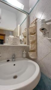 uma casa de banho com lavatório, espelho e toalhas em Central 9 Rooms em Ermoupoli