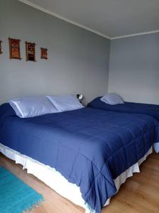 1 dormitorio con 2 camas y edredón azul en Casa Lago Rupanco, en Puerto Rico