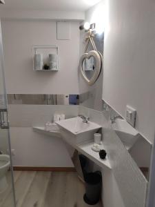 bagno bianco con lavandino e specchio di Residenza le Torri a Bologna